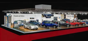 BMW Austria Messestand auf der Vienna Autoshow 2017 mit verschiedenen BMW Fahrzeugen in unterschiedlichen Farben, darunter grün, lila, rot und blau, sowie zwei BMW Motorrädern. Im Vordergrund ist der BMW i8. Der Bereich ist gut beleuchtet, und es sind Branding- und Informationsschilder sichtbar.