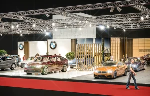 Auf der Messe Vienna Auto Show 2018 sind mehrere BMW Modelle unter hellen Lichtern ausgestellt, und die Menschen gehen umher, um die Fahrzeuge zu beobachten.