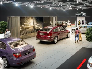 Auf der Messe Vienna Auto Show 2018 ist ein BMW 5 Grand Coupe Modell unter hellen Lichtern ausgestellt, eine Frau und ein Mann stehen davor und unterhalten sich.