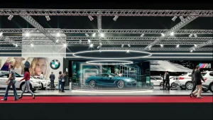 Ein tealfarbenes BMW 8er wird auf einer kreisrunden Plattform bei der Vienna Autoshow 2019 ausgestellt. Mehrere Personen in Geschäftskleidung stehen um das Auto herum, und moderne Beleuchtung und Großprints schmücken den Hintergrund. Im Vordergrund gehen Menschen auf einem roten Teppich herum
