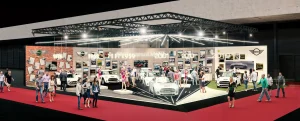 IAuf der Vienna Autoshow 2019 sind mehrere MINI Fahrzeuge, Schaufensterpuppen und eine Zeitleiste mit den Jahren 1959 bis 2019 zu sehen. An den Wänden hängen das Zeichen #60yearsofMINI und Bilder aus der Geschichte von MINI.
