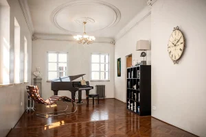 Visualisierung Nonntal Salzburg 3. Obergeschoss mit einem schwarzen Flügel, Buchregal, Büste und Schaukelliege