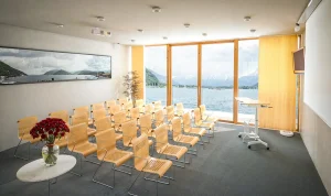 Seevilla Freiberg, Zell am See, Seminarraum mit Holzstühlen, Rednerpult, Beamer mit einem Blick auf den Zeller See